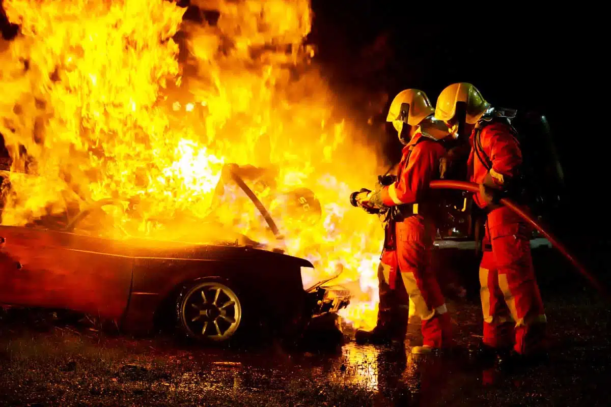 Deux pompiers luttent contre un incendie de véhicule.