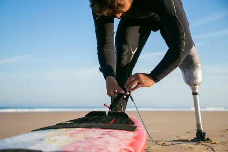 Un surfeur amputé d'une jambe prépare sa planche.