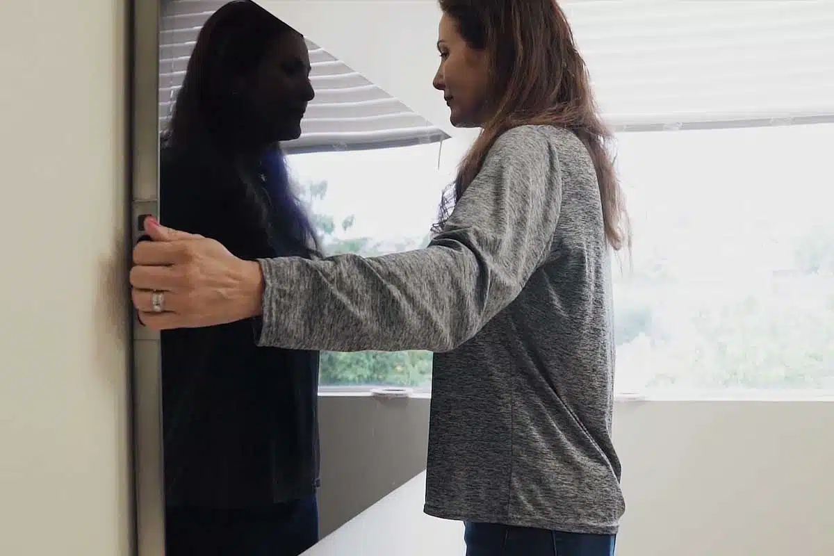 Une femme installe un téléviseur au mur.