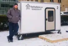 Un homme se tient contre une tiny house.