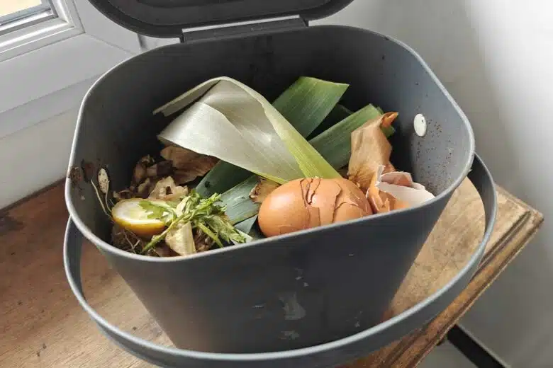 Une personne dépose des déchets alimentaires au compost.