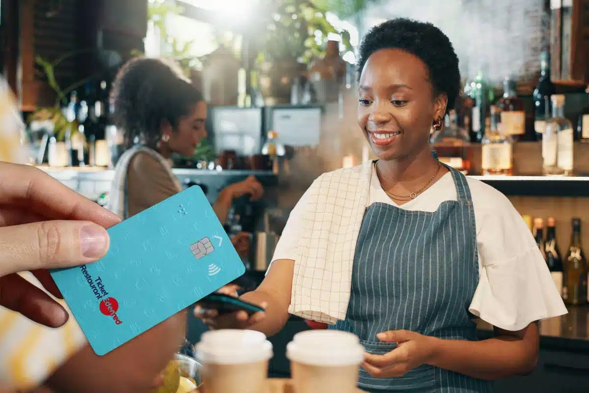 Une personne paie la note avec sa carte ticket resto.