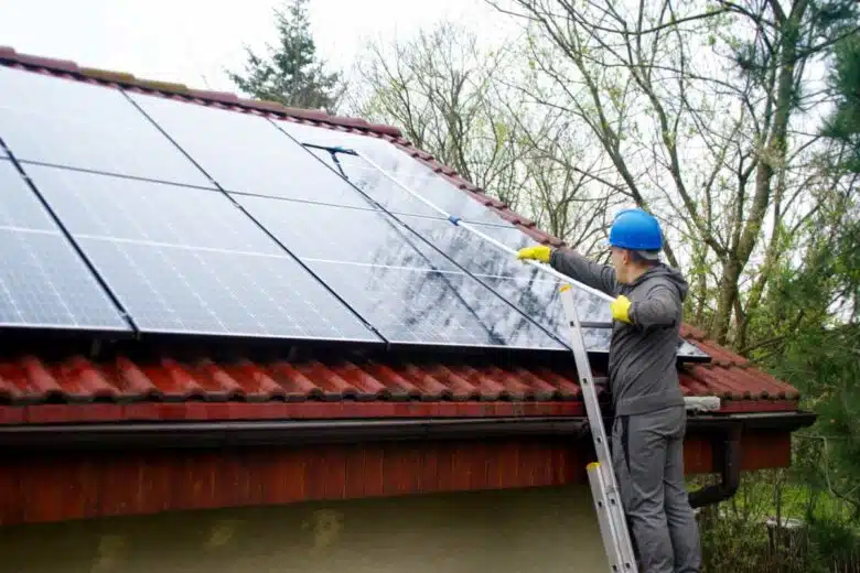 Un homme nettoie des panneaux solaires sur un toit.