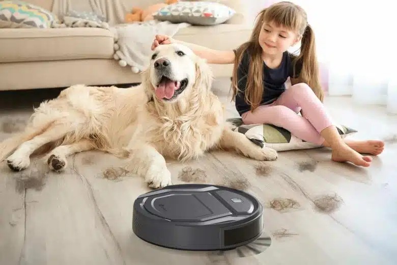 Un aspirateur robot travaille devant un chien et une petite fille.