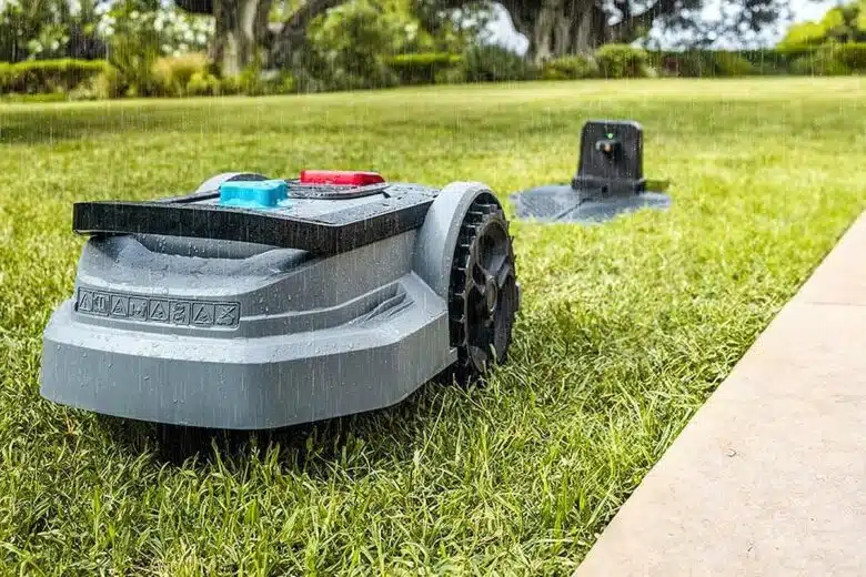 Un robot tondeuse revient à sa base sous la pluie.