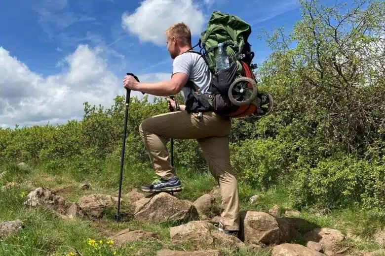 Un homme qui pratique le trekking avec un chariot transformé en sac à dos.