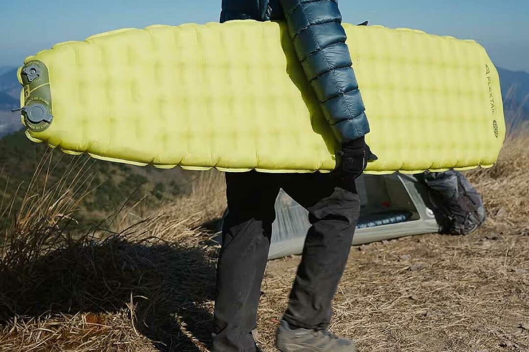 Un homme porte son matelas gonflable.