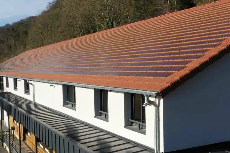 Toiture d'un bâtiment en zone historique rénové avec des tuiles solaires.