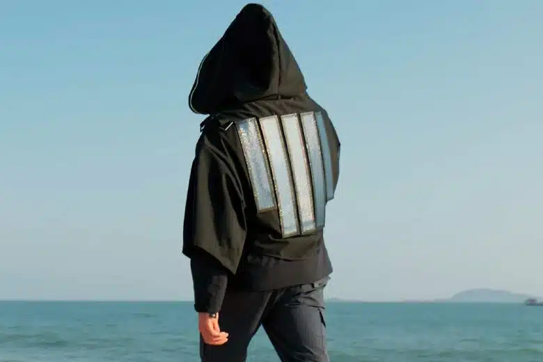 Une personne marche sur la plage avec un vêtement équipé de panneaux solaires.