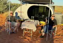 Un couple dine près de sa caravane.