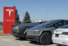 Des véhicules Tesla devant l'enseigne de la marque.