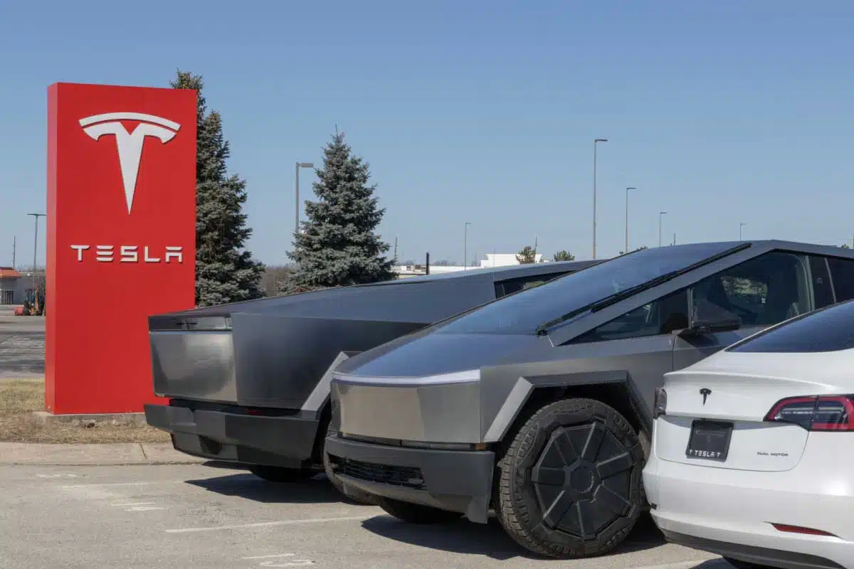 Des véhicules Tesla devant l'enseigne de la marque.